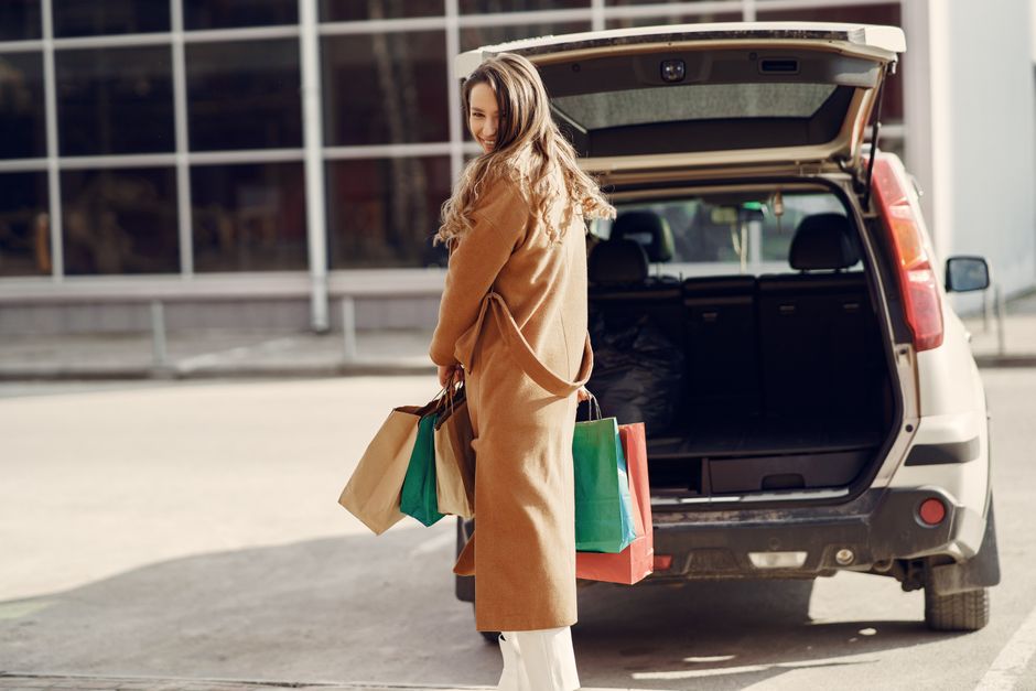 쇼핑 bags를 가진 스타일리시한 여성이 자신의 SUV 옆에 서서 우아함과 기쁨을 발산합니다.